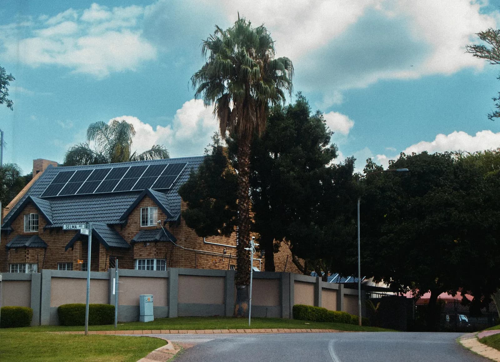 A house with solar panels on its roof among palm trees